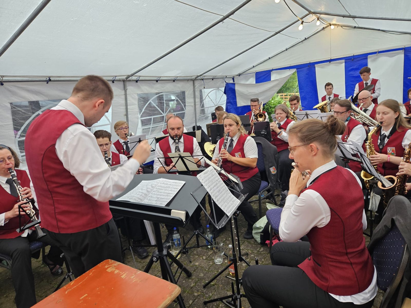 Die Stammkapelle spielt in Uniform im Festzelt, der Dirigent von hinten