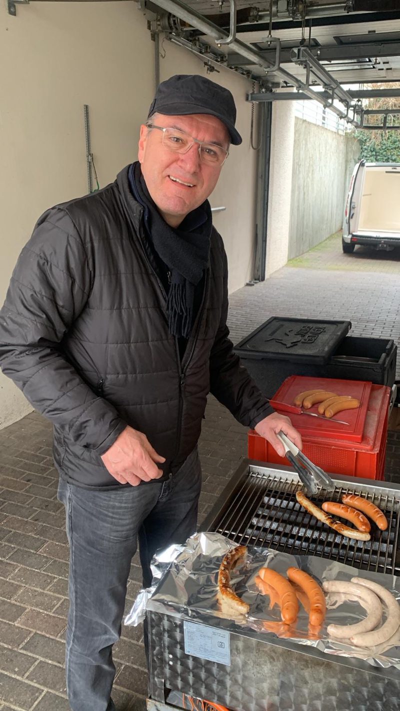Ein Musiker in Winterjacke wendet lachend die Würste