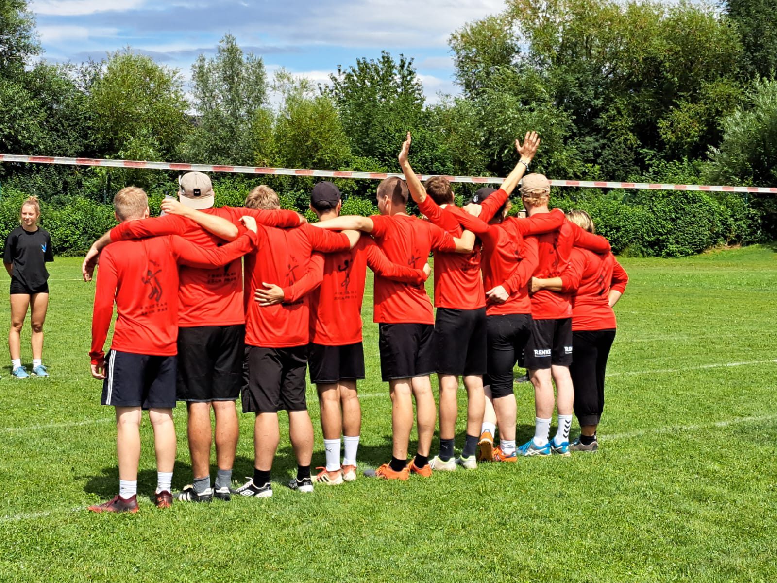 Das Team „Freitags isch Prob“ in roten Trikots bildet einen Kreis am Spielfeld