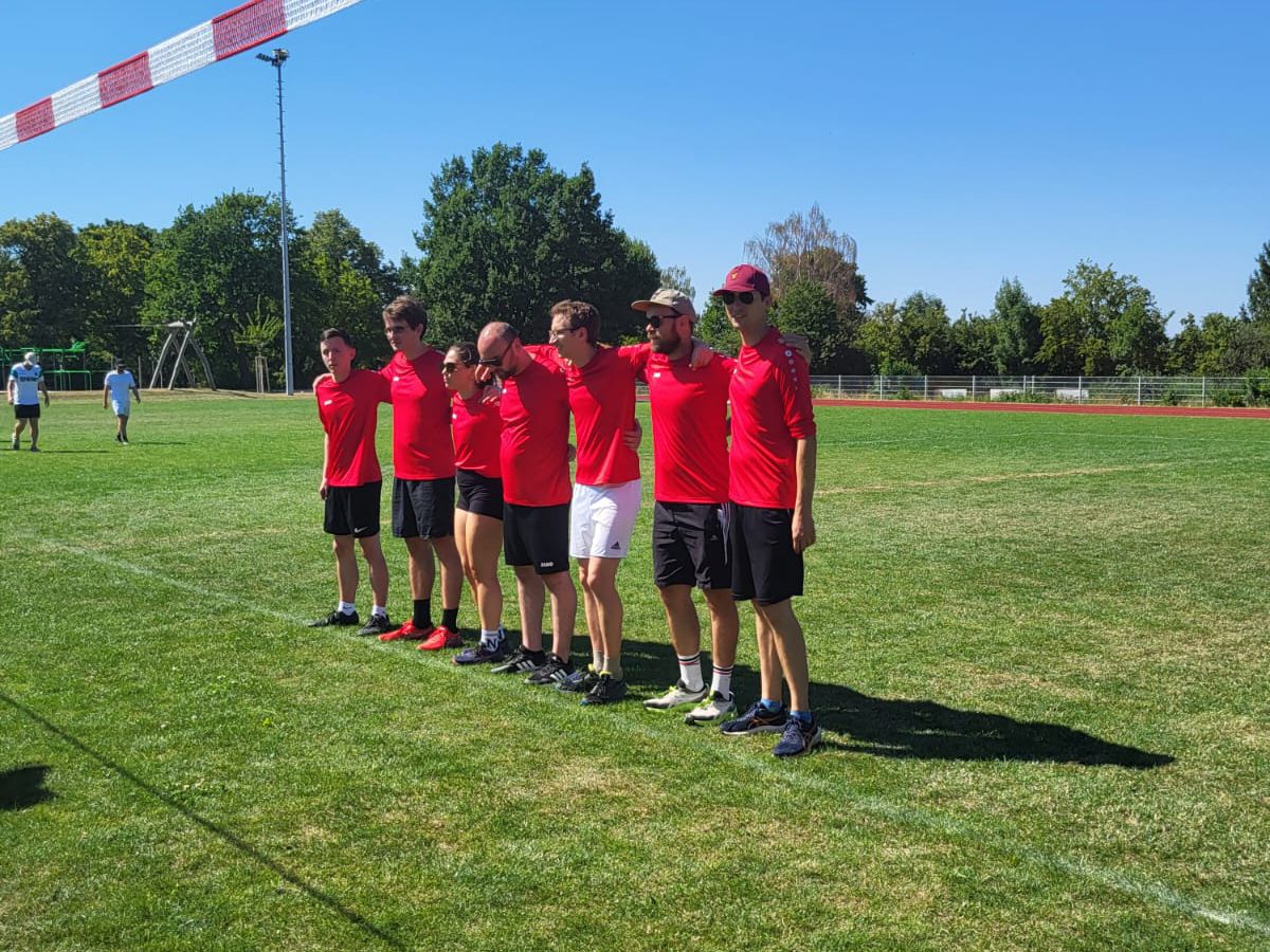 Sieben aus dem Team stehen Arm in Arm an der Seitenlinie